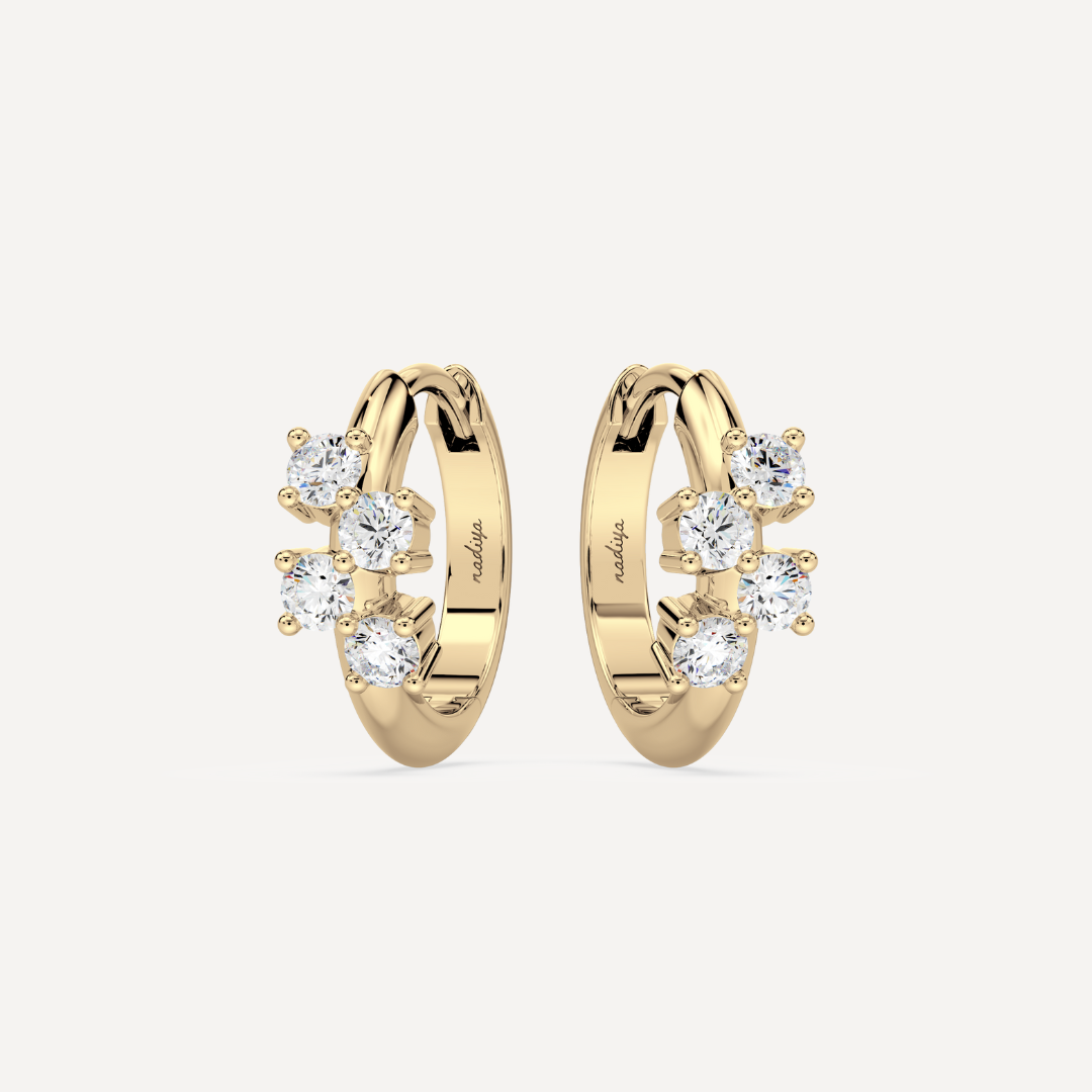 a solid gold hoop earring huggie with diamonds against a creamy white background by nadiya jewelry