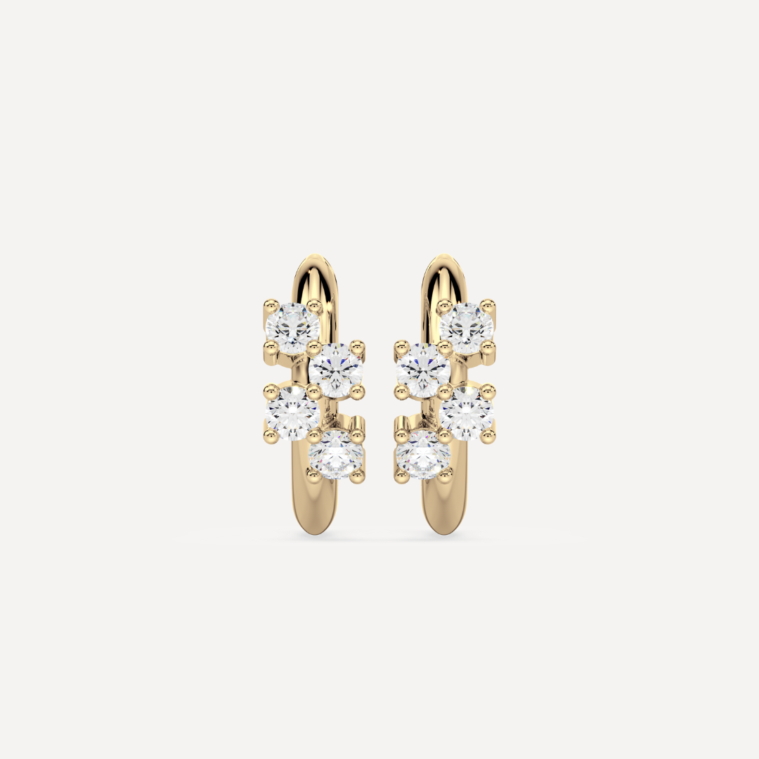 a solid gold hoop earring huggie with diamonds against a creamy white background by nadiya jewelry