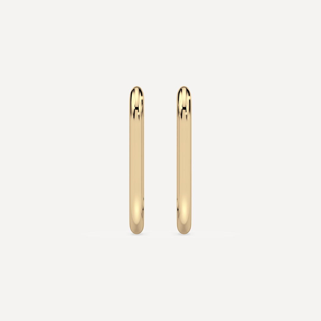 solid gold oval hoops against a creamy white background by nadiya jewelry