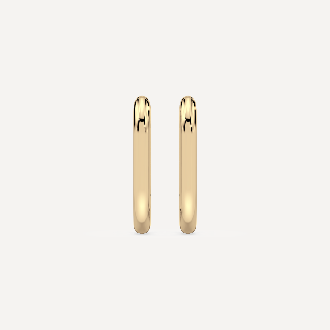 solid gold oval hoops against a creamy white background by nadiya jewelry