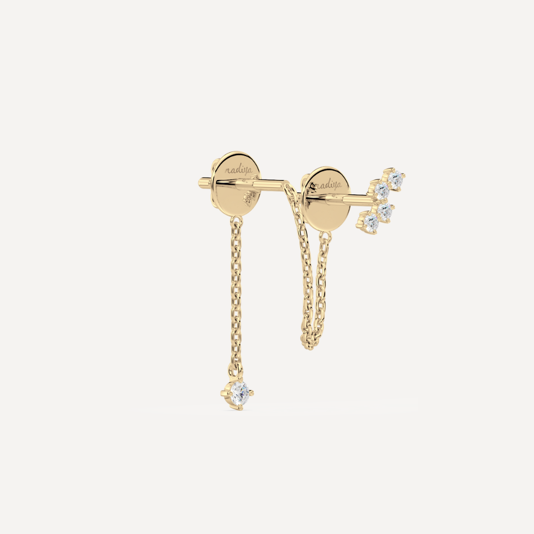 A solid gold earring with a small chain and multiple stones attached to it by nadiya jewelry
