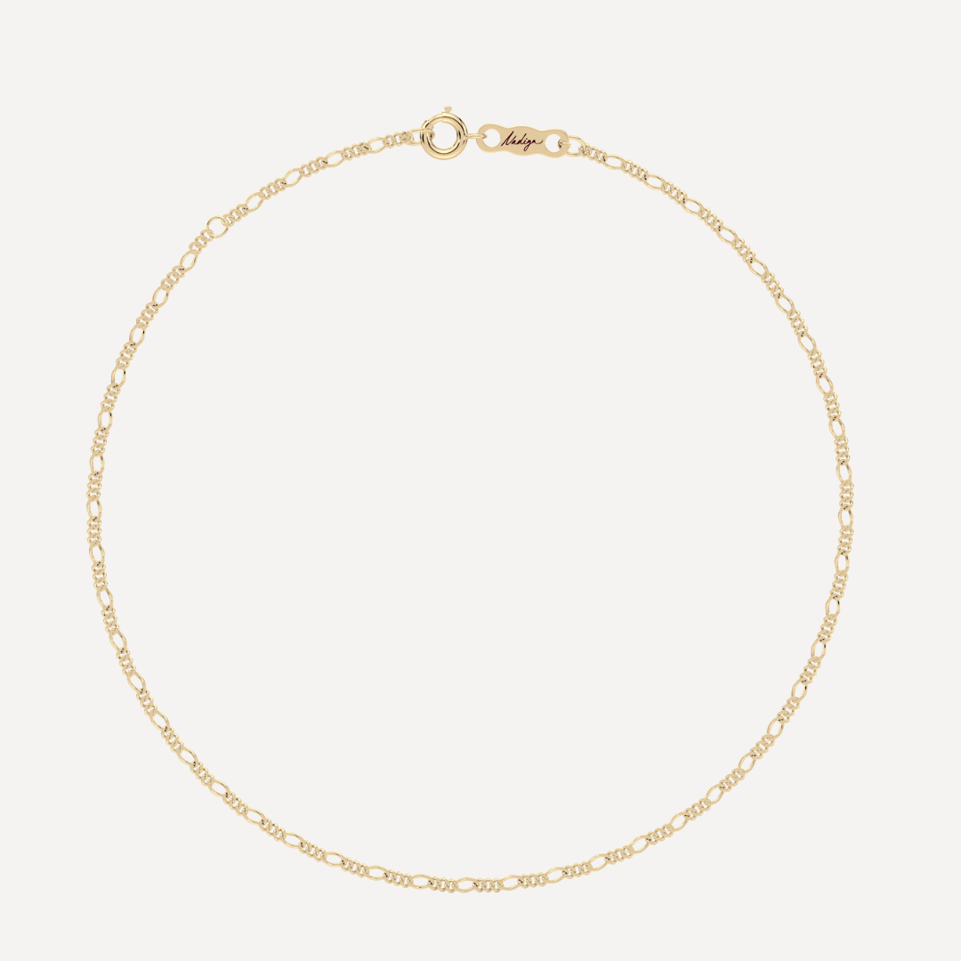 hero image of a solid gold figaro chain bracelet against a cream background