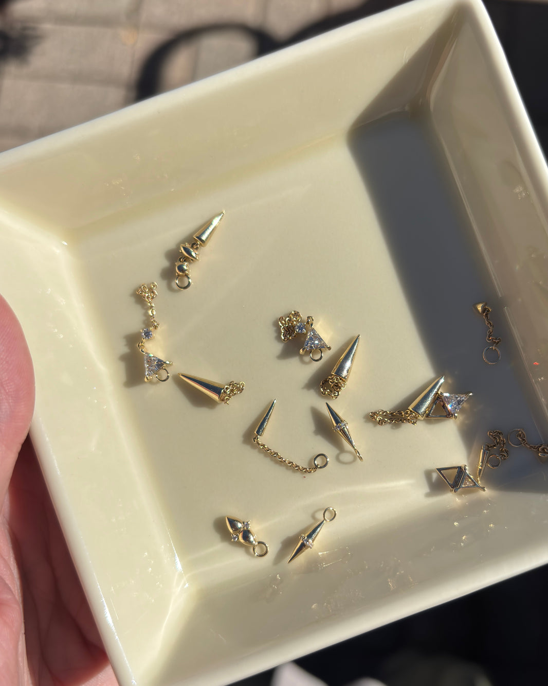 a jewelry dish filled with solid gold earrings and hoop charms