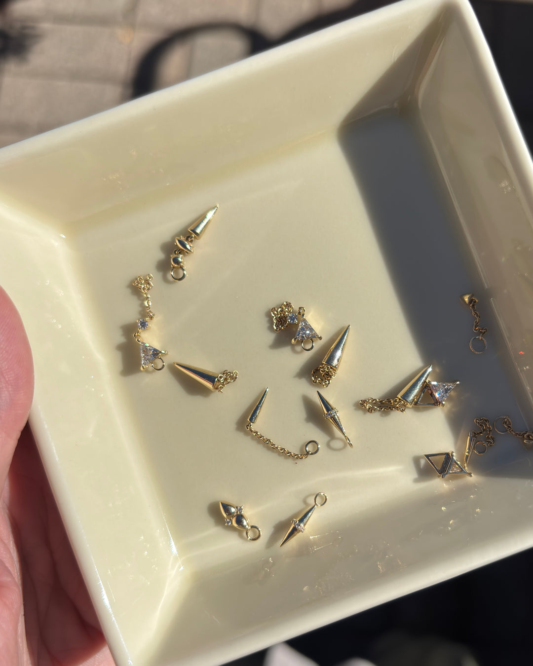 a jewelry dish filled with solid gold earrings and hoop charms