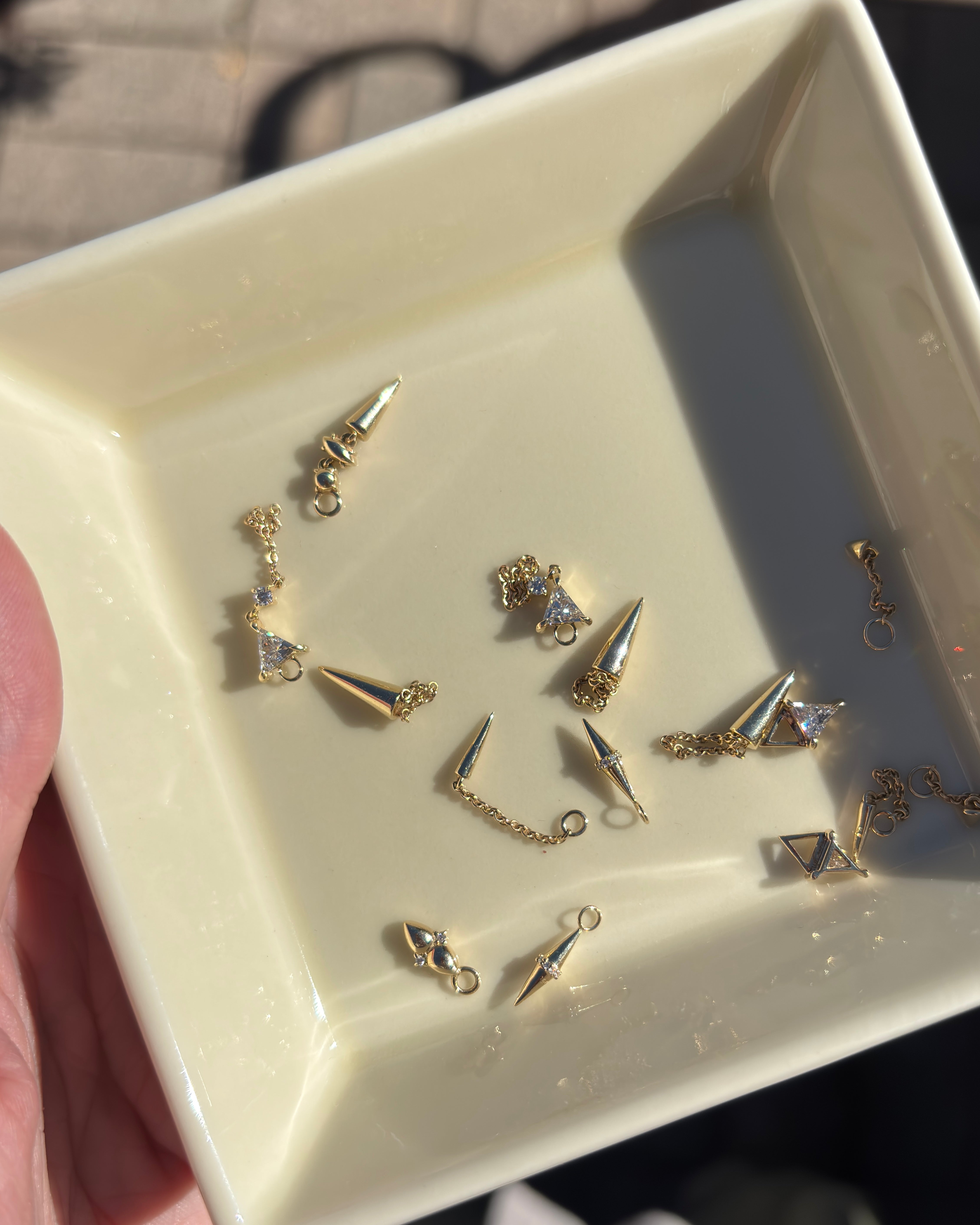 a jewelry dish filled with solid gold earrings and hoop charms