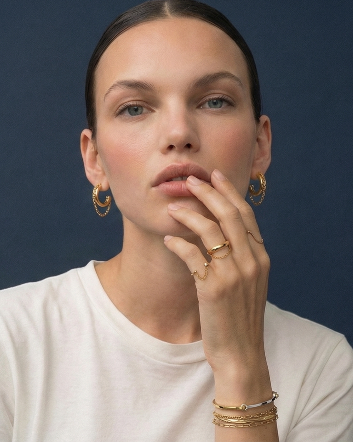 Woman wearing gold jewelry against a dark blue background
