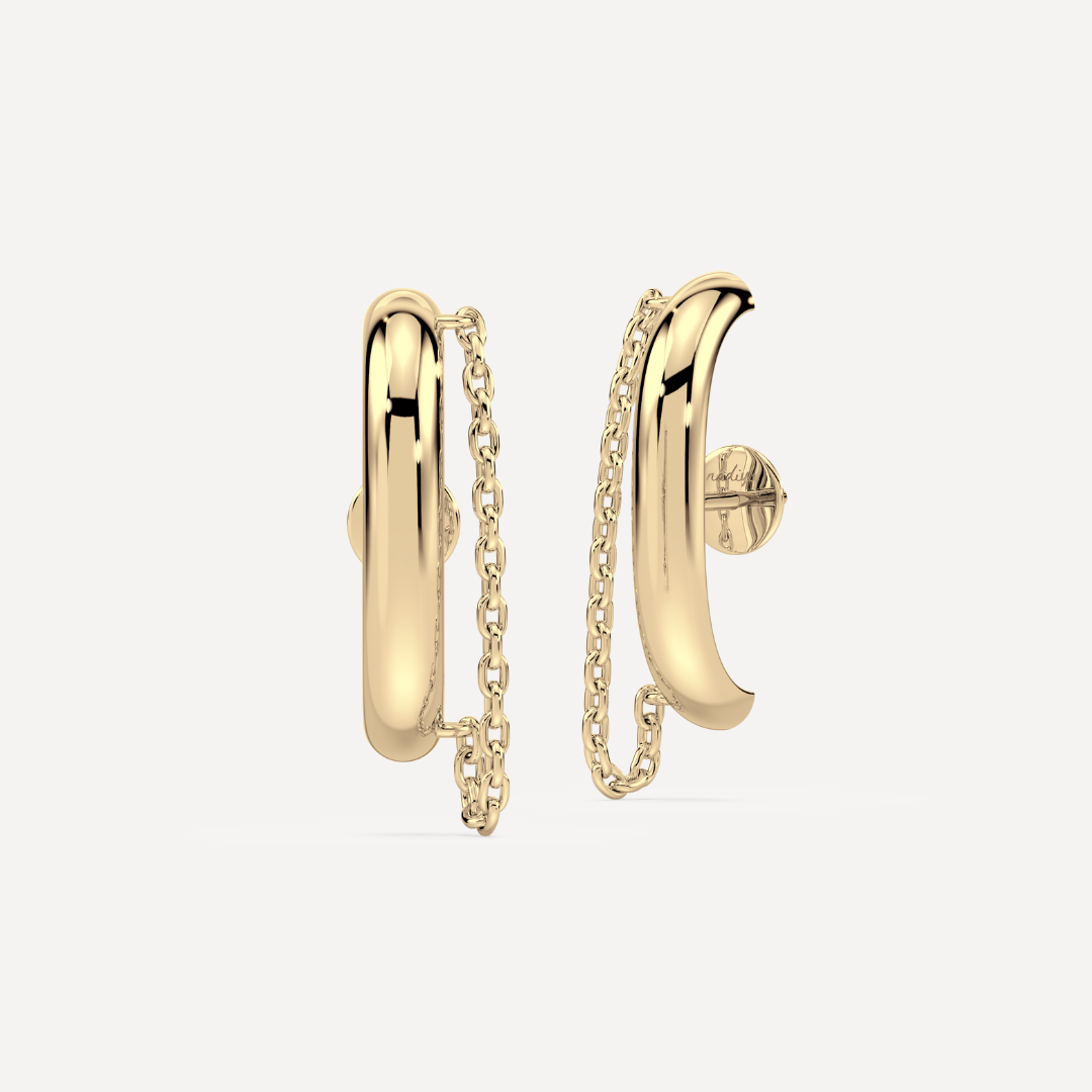 This image displays a pair of elegant ear suspender earrings, crafted in a striking gold-tone material. The design features a sleek, minimalist aesthetic with each earring consisting of a smooth, curved bar suspended from a small circular stud, connected by a delicate chain to another bar by nadiya jewelry
