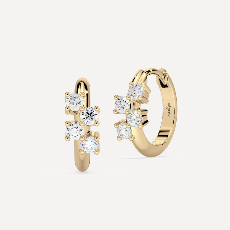 a solid gold hoop earring huggie with diamonds against a creamy white background by nadiya jewelry
