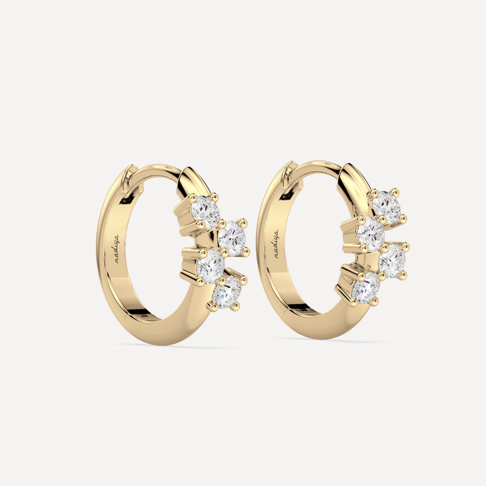 a solid gold hoop earring huggie with diamonds against a creamy white background by nadiya jewelry