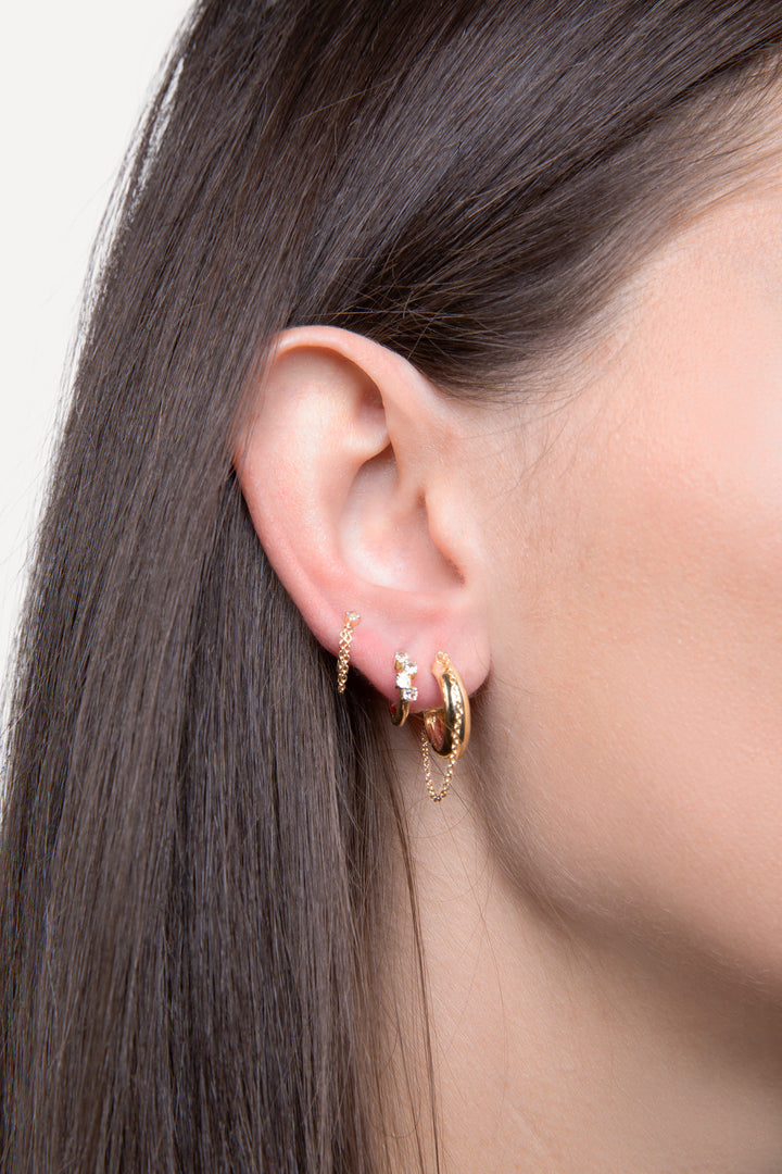 solid gold earrings with chain and diamond details on woman in three ear holes