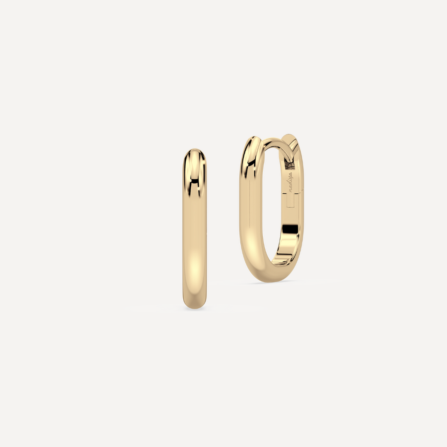solid gold oval hoops against a creamy white background by nadiya jewelry