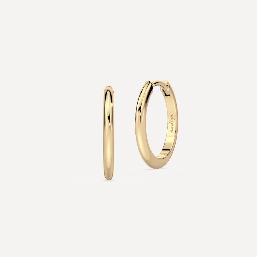 solid gold round hoops against a creamy white background by nadiya jewelry