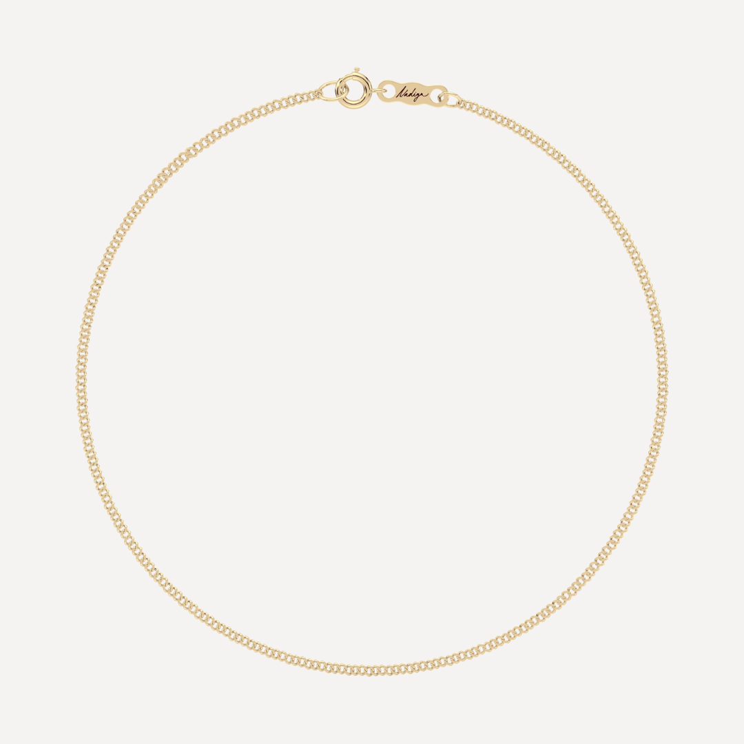 hero image of a solid gold single curb chain bracelet against a cream background 