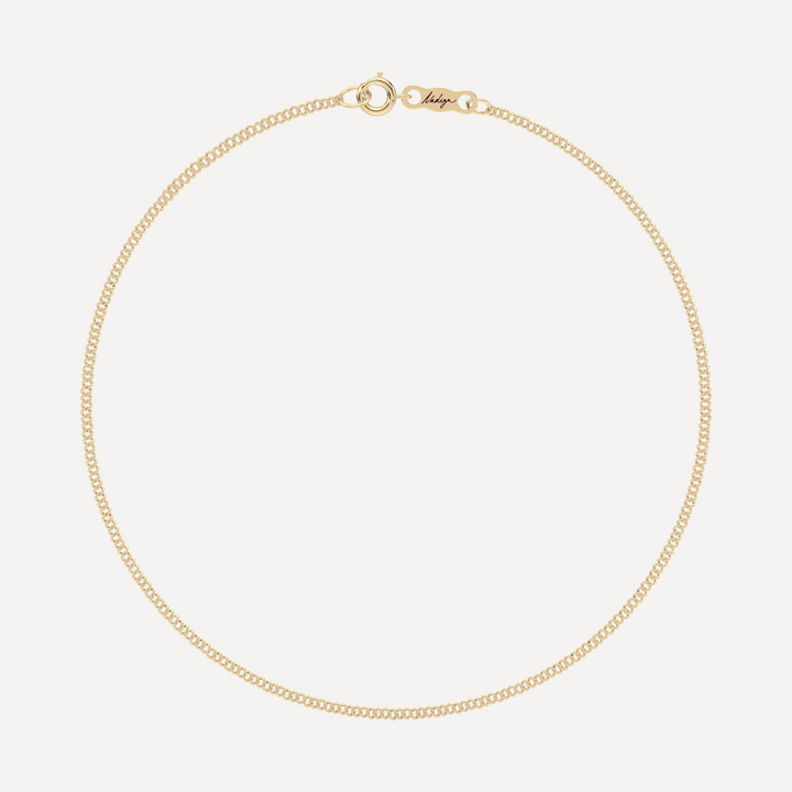 hero image of a solid gold single curb chain bracelet against a cream background 