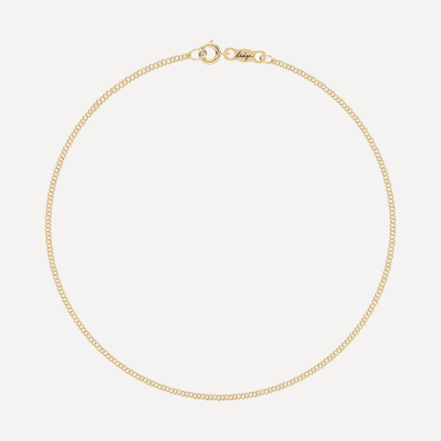 hero image of a solid gold single curb chain bracelet against a cream background 
