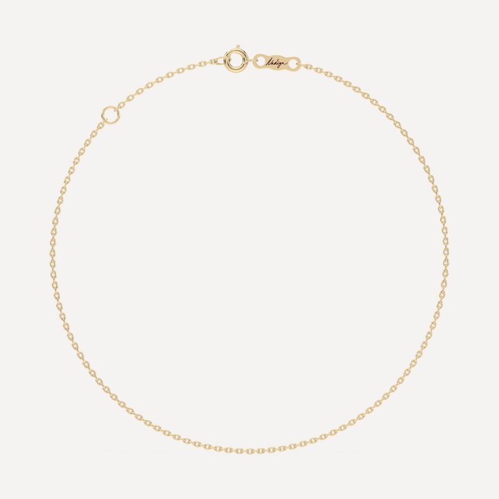 hero image of a solid gold cable chain bracelet against a cream background 