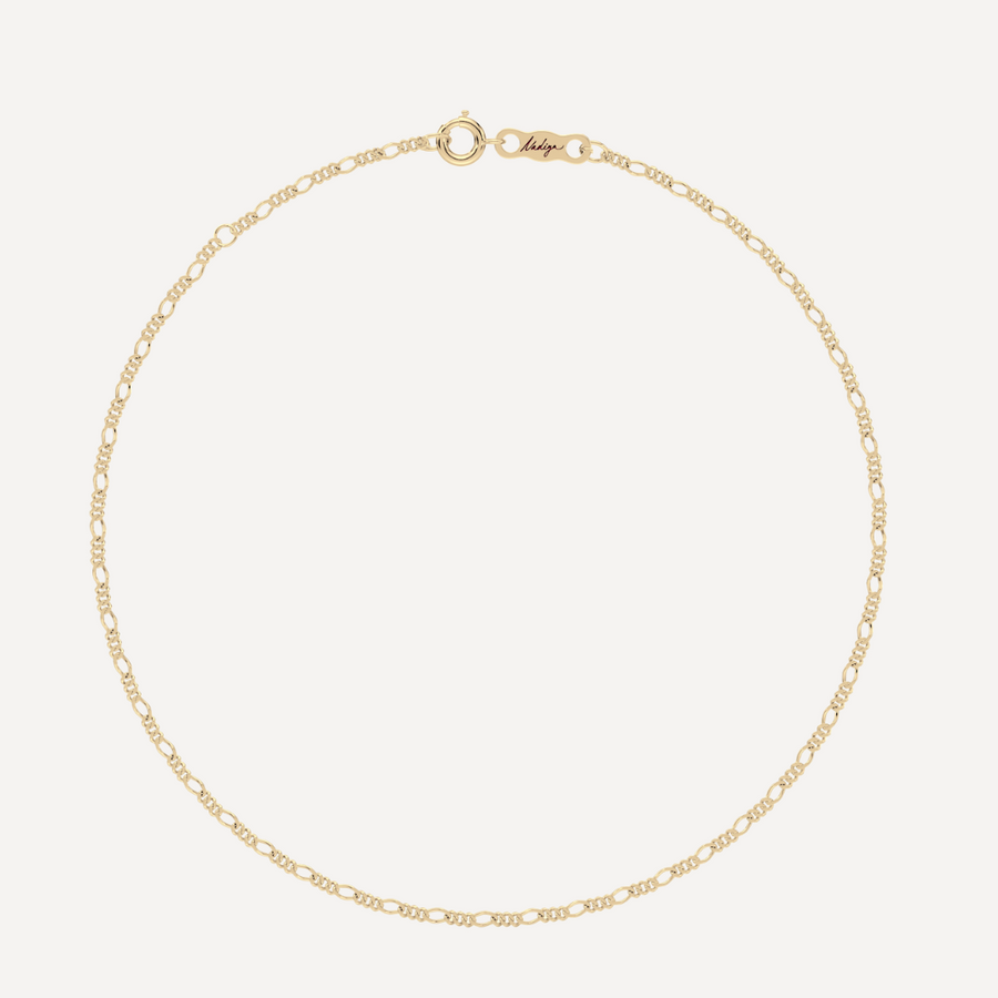 hero image of a solid gold figaro chain bracelet against a cream background 