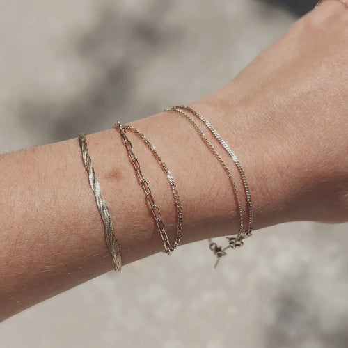 Minimalist solid gold chain bracelets for women, layered on wrist for everyday fine jewelry style.